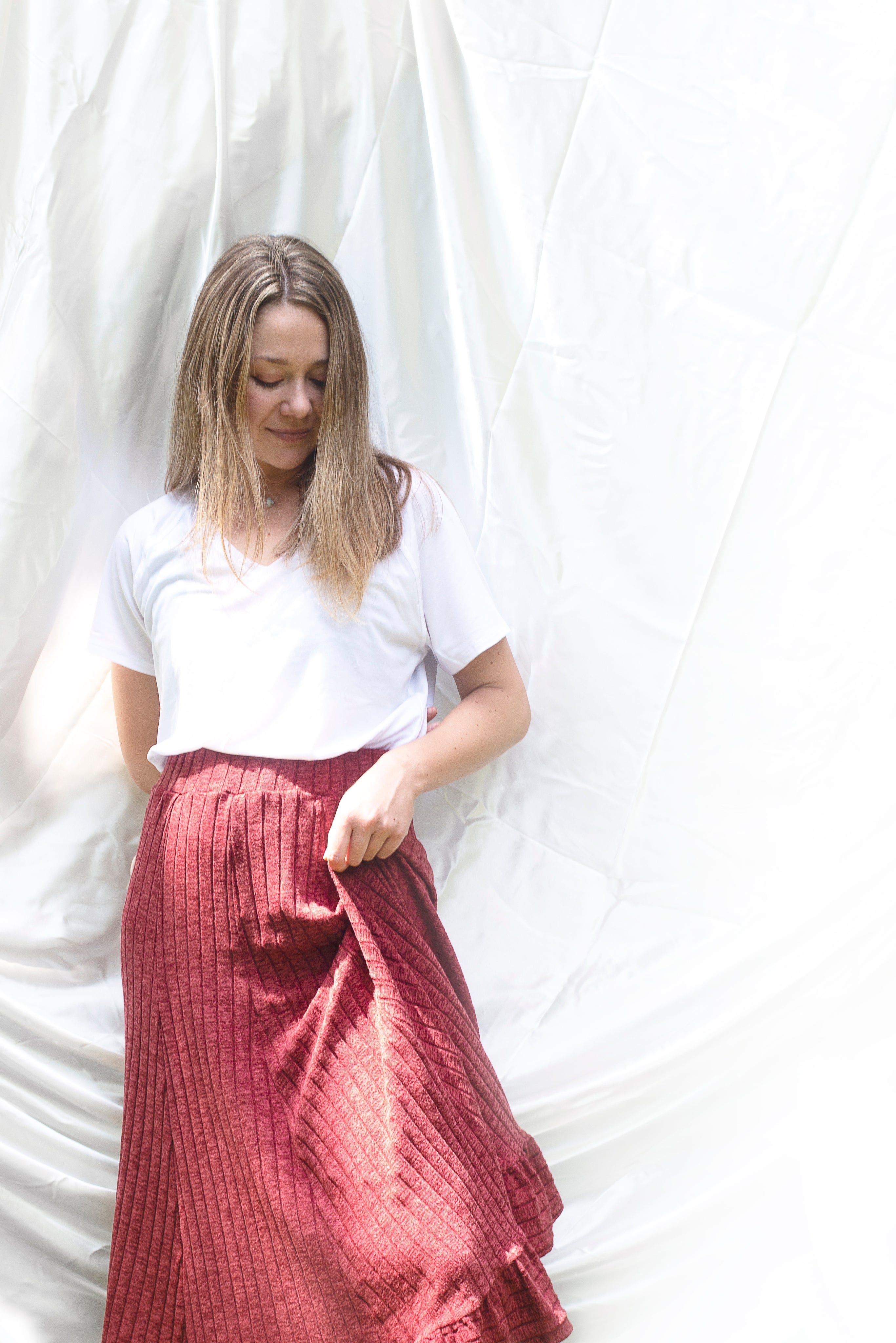 files/woman-in-white-shirt-and-red-skirt-against-cloth-backdrop.jpg